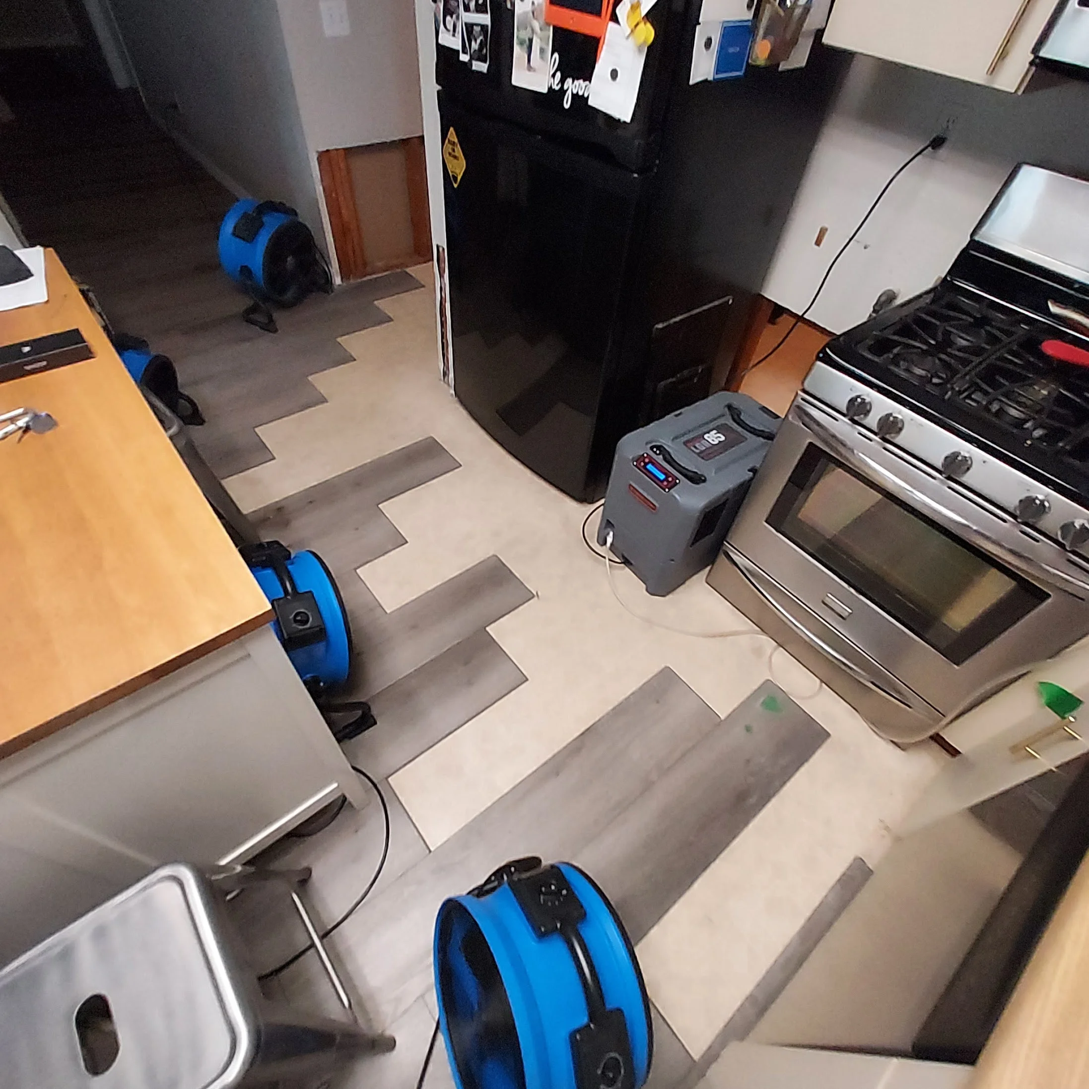Drying fans and dehumidifier set up in kitchen with flooring and cabinet removed